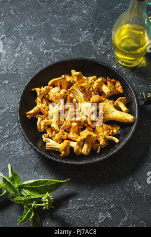 Chanterelles fraîches dans une casserole noire sur une table en pierre. Banque D'Images