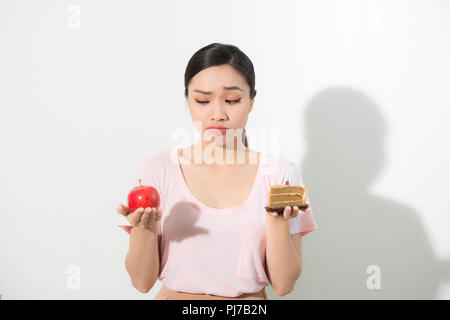 Femme tient en main et doux gâteau pomme fruit choisir, essayant de résister à la tentation, faire les bons choix alimentaires. Dilemme de régime de perte de poids la gourmandise Banque D'Images