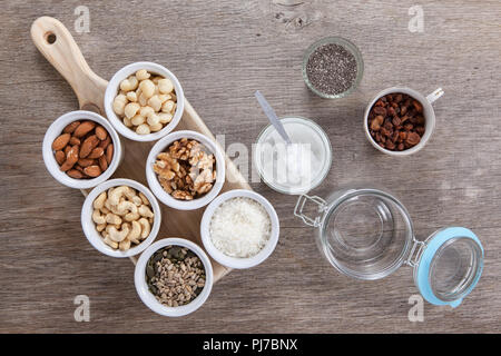 Ingrédients pour les céréales granola paléo libre : les noix, les graines, les raisins secs, flocons de noix de coco, huile de coco et chia Banque D'Images