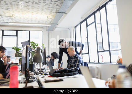 Les hommes d'affaires travaillant à l'ordinateur portable en open plan office Banque D'Images