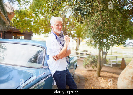 Portrait homme confiant biting pointe de voiture à lunettes Banque D'Images