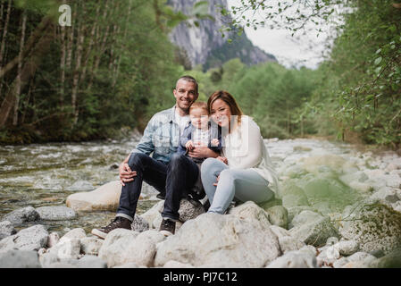 Portrait des parents et bébé assis sur des roches à Riverside Banque D'Images