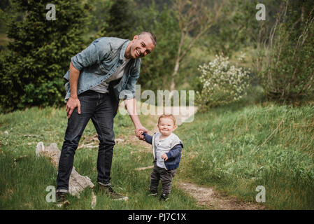 Portrait père et fils bébé marche sur chemin herbeux Banque D'Images