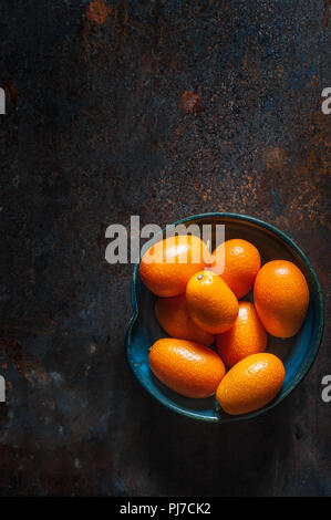 Kumquat fruits sur une plaque en céramique noire sur un fond sombre. Vue de dessus Banque D'Images