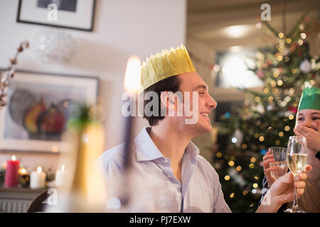 Happy father and daughter in paper crowns eau potable et champagne au dîner de Noël aux chandelles Banque D'Images
