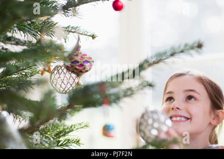 Smiling girl looking up at ornaments on Christmas Tree Banque D'Images