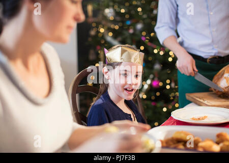 Smiling girl wearing paper crown at Christmas dinner Banque D'Images