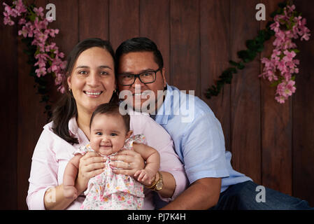 Jeune couple avec un petit bébé portrait sur fond de bois foncé Banque D'Images