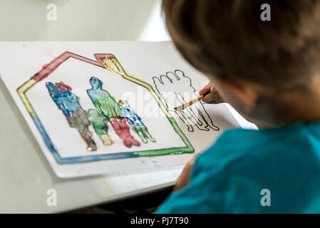 La coloration de l'enfant dans un sketch d'une famille à l'aide d'un pinceau et les peintures à l'aquarelle. Banque D'Images