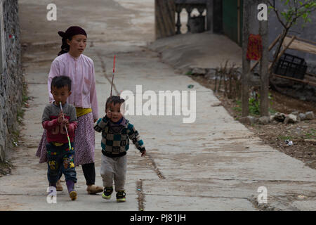 Ha Giang, Vietnam - Mars 18, 2018 : Mère et enfants marcher dans une rue de village de came du poumon dans les montagnes du nord du Vietnam Banque D'Images