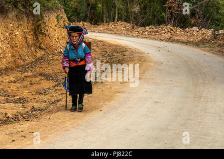 Ha Giang, Vietnam - Mars 18, 2018 : femme marche sur une route poussiéreuse près de champs agricoles dans le nord du Vietnam Banque D'Images