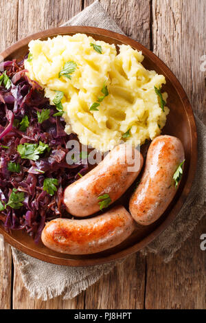 Servi avec une purée de pommes de terre compotée de chou rouge saucisses frites et close-up sur une plaque sur une table. Haut Vertical Vue de dessus Banque D'Images