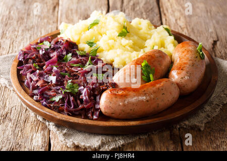 Saucisses allemandes traditionnelles avec une purée de pommes de terre et de choucroute. Wurst Bratwurst ou avec du chou rouge close-up sur une plaque sur une table. L'horizontale Banque D'Images