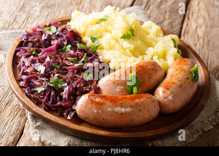 Saucisses grillées à la vapeur avec du chou rouge (choucroute) et des pommes de terre sur une plaque sur une table horizontale. Banque D'Images