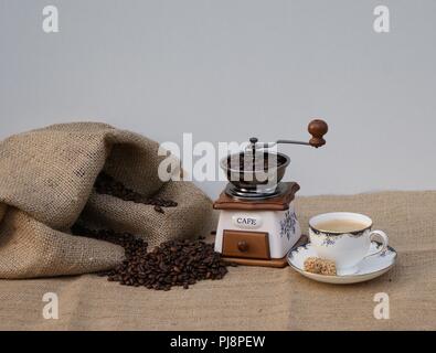 Nature morte avec un moulin à café nostalgique et une tasse de café avec café fraîchement préparé Banque D'Images