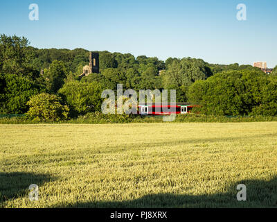 Leeds, Angleterre, Royaume-Uni - 30 juin 2015 : une Classe 333 Northern Rail train passager électrique sur la ligne passe Airedale les ruines de Kirkstall Abbey, partie Banque D'Images