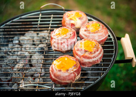 Faire de la bière fait maison peut Bacon les galettes sur le barbecue. Préparer les galettes farcies, enrobé de bacon et les grillades sur la chaleur indirecte dans la nature à bac Banque D'Images