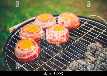 Faire de la bière fait maison peut Bacon les galettes sur le barbecue. Préparer les galettes farcies, enrobé de bacon et les grillades sur la chaleur indirecte dans la nature à bac Banque D'Images