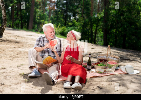 Couple de retraités manger melon d'eau avoir pique-nique sur la plage Banque D'Images