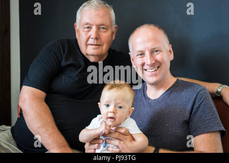 Grand-père, père et fils s'asseoir ensemble et à la caméra en Banque D'Images