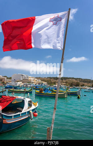 Brandissant le drapeau de Malte dans le vent en Marsaxlokk, Malte Banque D'Images