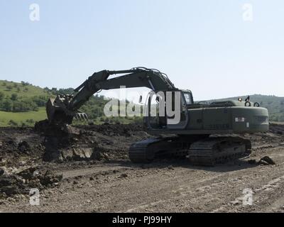 Un soldat des Forces terrestres creuse un fossé de drainage à l'aide d'une excavatrice en collaboration avec la 961e compagnie du génie, de l'armée américaine se réserve, au cours de leur ferme château 2018 rotation au Centre national de formation conjointe, Cincu, la Roumanie, le 6 juillet 2018. Les deux militaires ont travaillé ensemble pour une formation polyvalente sur l'équipement et complète à l'appui de projets ingénieur résoudre l'Atlantique. Banque D'Images