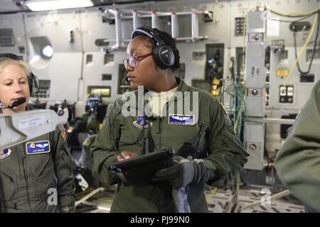 U.S. Air Force d'un membre de la 1re classe Sylvia Bannister (milieu) un membre de la 156e Escadron d'évacuation aéromédicale (AES), examine son guide de formation pour les cours de formation médicale à bord d'un C-17 Globemaster III, après avoir quitté le Nord Carolina Air National Guard Base, Charlotte Douglas International Airport, le 9 juillet 2018. C'est la première mission pour la Caroline du Nord Air National Guard avec le C-17 et c'est le transport de l'équipement et le personnel de la 156e à la Wisconsin Sea Air National Guard Base à Volk Field pour un exercice d'entraînement. Banque D'Images