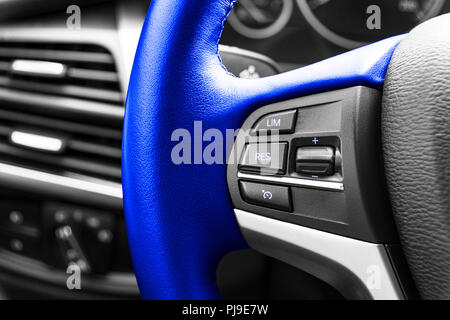Boutons de contrôle de croisière sur le bleu volant d'une voiture moderne. Détails intérieurs de voiture. Esthétique auto Banque D'Images