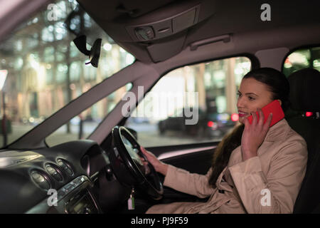 Businesswoman talking on smart phone en voiture à la nuit Banque D'Images