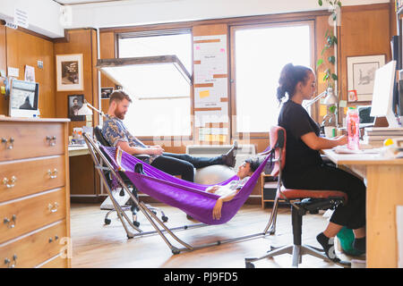 Creative designers relaxing in hammock in office Banque D'Images