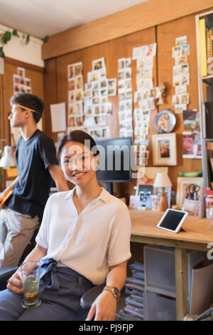 Portrait souriant, confiant creative businesswoman drinking tea in office Banque D'Images