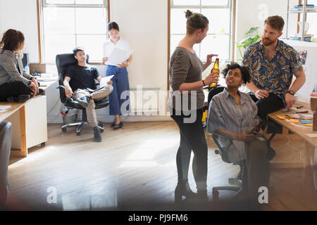 Les gens d'affaires créatrices de boire une bière et talking in office Banque D'Images