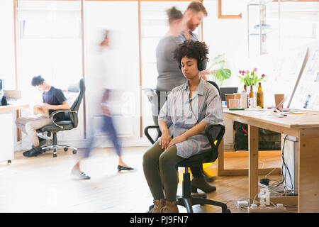 Serene woman meditating with headphones in office Banque D'Images