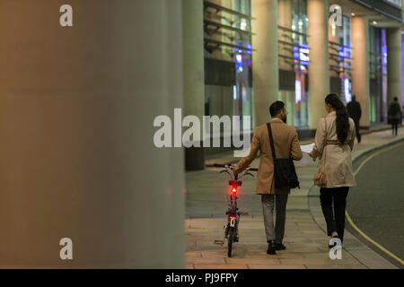 Les gens d'affaires avec location marche sur trottoir urbain de nuit Banque D'Images