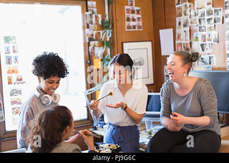 Creative designers féminins de manger des sushis dans office Banque D'Images