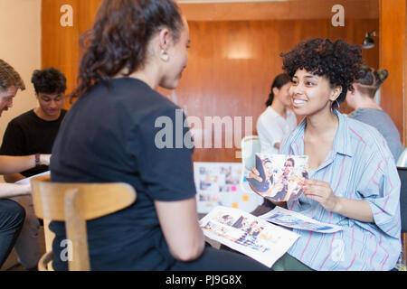 Smiling creative designers femmes discutant des épreuves en fonction de la photo Banque D'Images