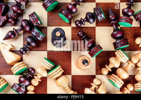 Une photo prise à la verticale d'une situation d'échecs en échec et mat avec presque tous les morceaux tombés sur l'échiquier, une métaphore pour la guerre Banque D'Images
