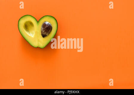 Heart-shaped tranches d'avocat sur fond orange Banque D'Images