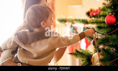 Photo gros plan de l'adorable petit garçon mettre des décorations sur Chrismtas tree Banque D'Images