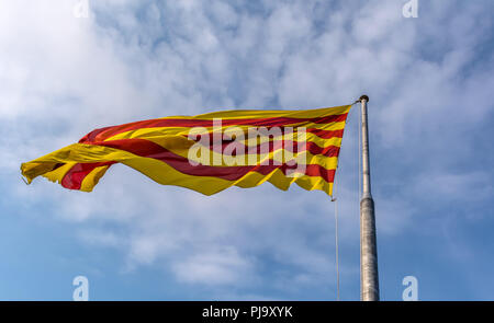 Brandissant le drapeau de la Catalogne dans la brise contre le ciel bleu. Le drapeau est appelé la Senyera drapeau (en catalan) et se compose de quatre bandes rouges sur fond jaune Banque D'Images