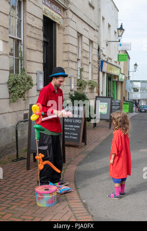 Vendeur de ballons faire un ballon animal pour une jeune fille à Stroud farmers market. Stroud, Gloucestershire, Angleterre Banque D'Images