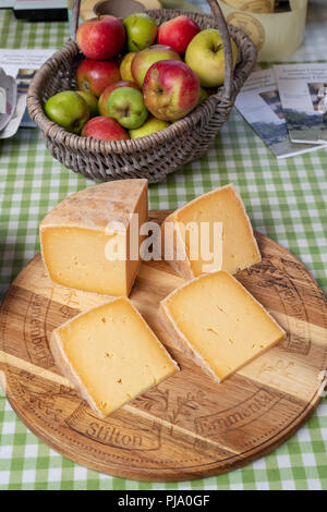 Le fromage et les pommes en vente sur un étal au marché des fermiers de Stroud. Stroud, Gloucestershire, Angleterre Banque D'Images