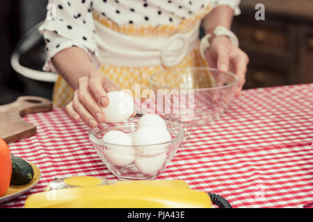 Cropped shot de femme au foyer en maillot à pois avec des oeufs et omelette pour bol Banque D'Images