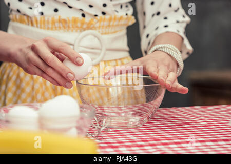 Cropped shot de femme au foyer dans le bol d'oeufs rupture pour omelette Banque D'Images