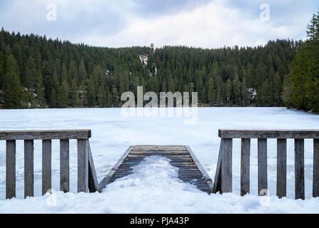 Paysage avec pont de bois enneigés et l'eau gelée du lac Mummelsee, entouré de forêt de sapins, dans les montagnes de la Forêt Noire, en Allemagne. Banque D'Images