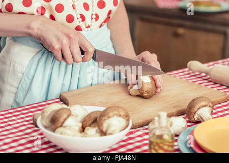 Cropped shot de femme au foyer dans la chemise à pois cuisine champignons au coupe Banque D'Images