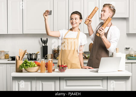 Couple avec smartphone selfies lors de la cuisson dans la cuisine Banque D'Images