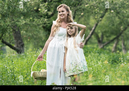 Adorable fille et mère tenant panier en osier dans Orchard Banque D'Images