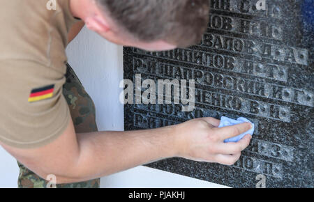 06.09.2018, Brandebourg, Lebus : un soldat allemand nettoie une plaque commémorative portant les noms de soldats de l'Armée Rouge tué dans la seconde guerre mondiale sur la sépulture de guerre soviétique. Le 7.9.2018, 100 soldats soviétiques tombés lors de la Seconde Guerre mondiale seront intégrées ici. Les restes des soldats ont été retrouvés au cours des derniers mois par l'resetters ; de la Commission des sépultures de guerre allemande (Volksbund Deutsche Kriegsgräberfürsorge e. V.) dans l'état de Brandebourg. Les soldats de l'Armée Rouge sont enterrés dans le cadre de la mission traditionnelle de travail germano-russe des forces armées allemandes et l'armée russe. Russi Banque D'Images