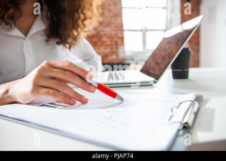 Image en gros plan d'un travailleur de l'analyse de données statistiques financières. Businesswoman ou comptable hand holding pencil travaillant sur calculatrice pour calculer fi Banque D'Images